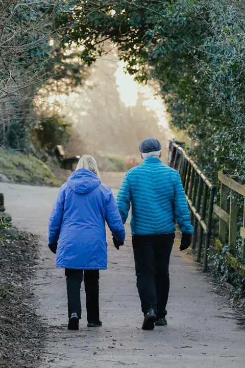 A couple in their fifties walking outdoors together.